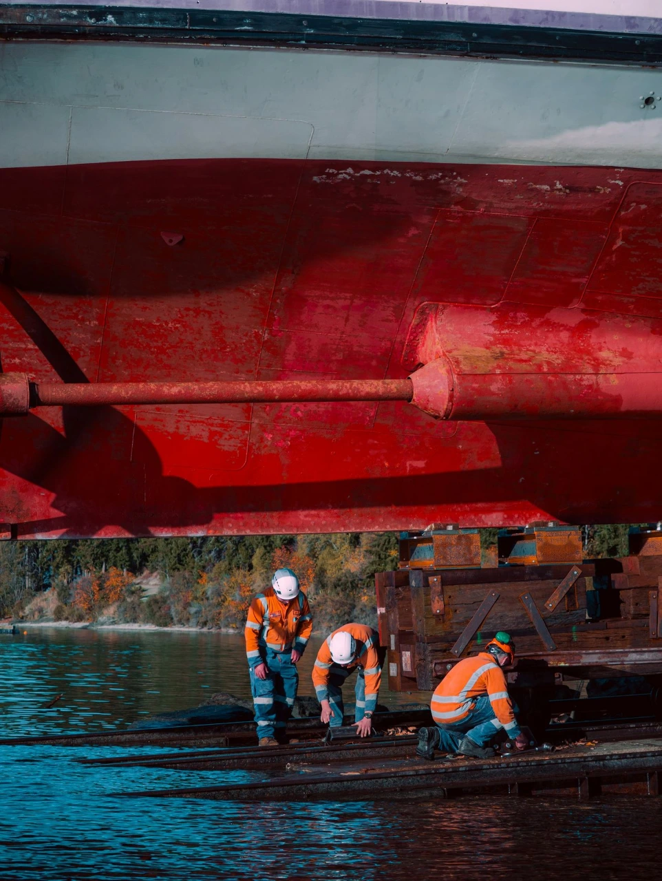 Workers inspect the underside of a boat.